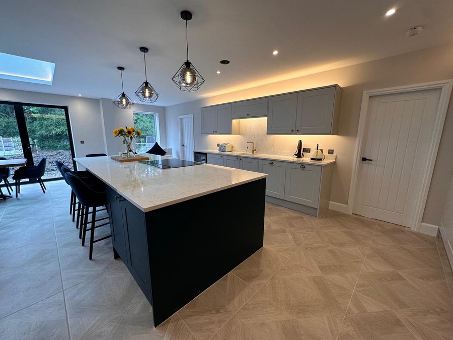 Shaker kitchen with navy island, quartz worktops and herringbone tiled floor by Abacus Joinery